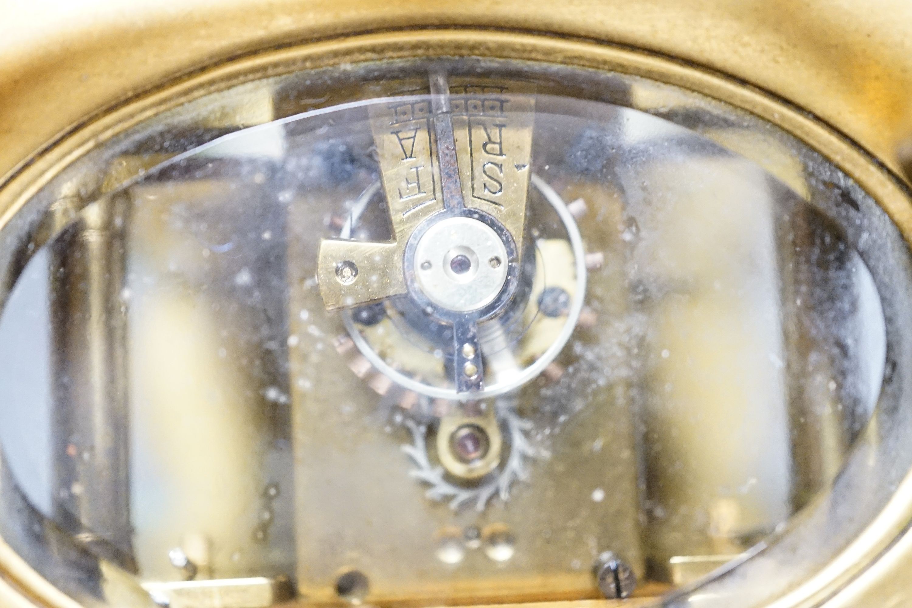 An oval brass cased carriage timepiece and associated carrying case.